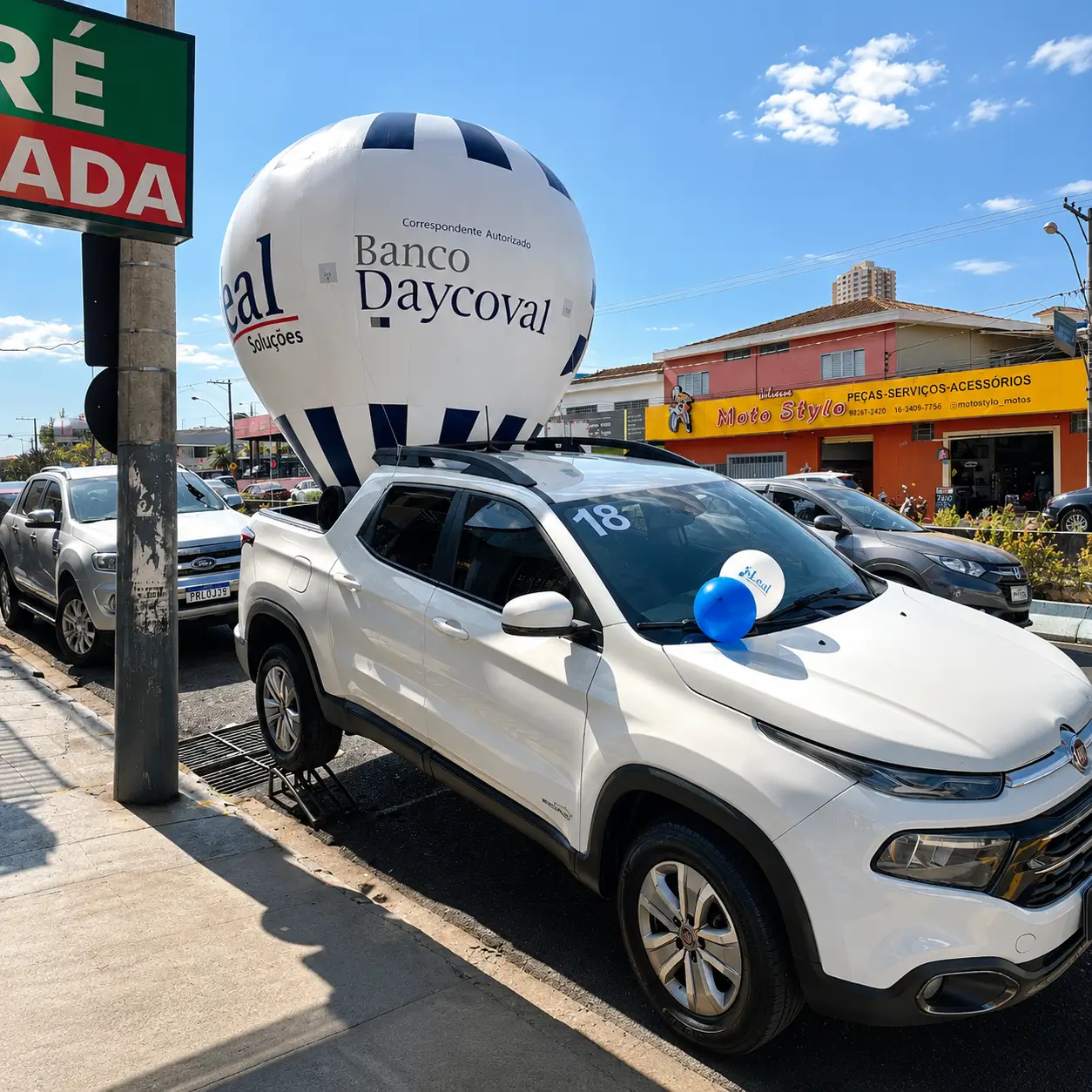 Balão inflável personalizado do Banco Daycoval instalado em veículo promocional durante ação de marketing em avenida comercial.