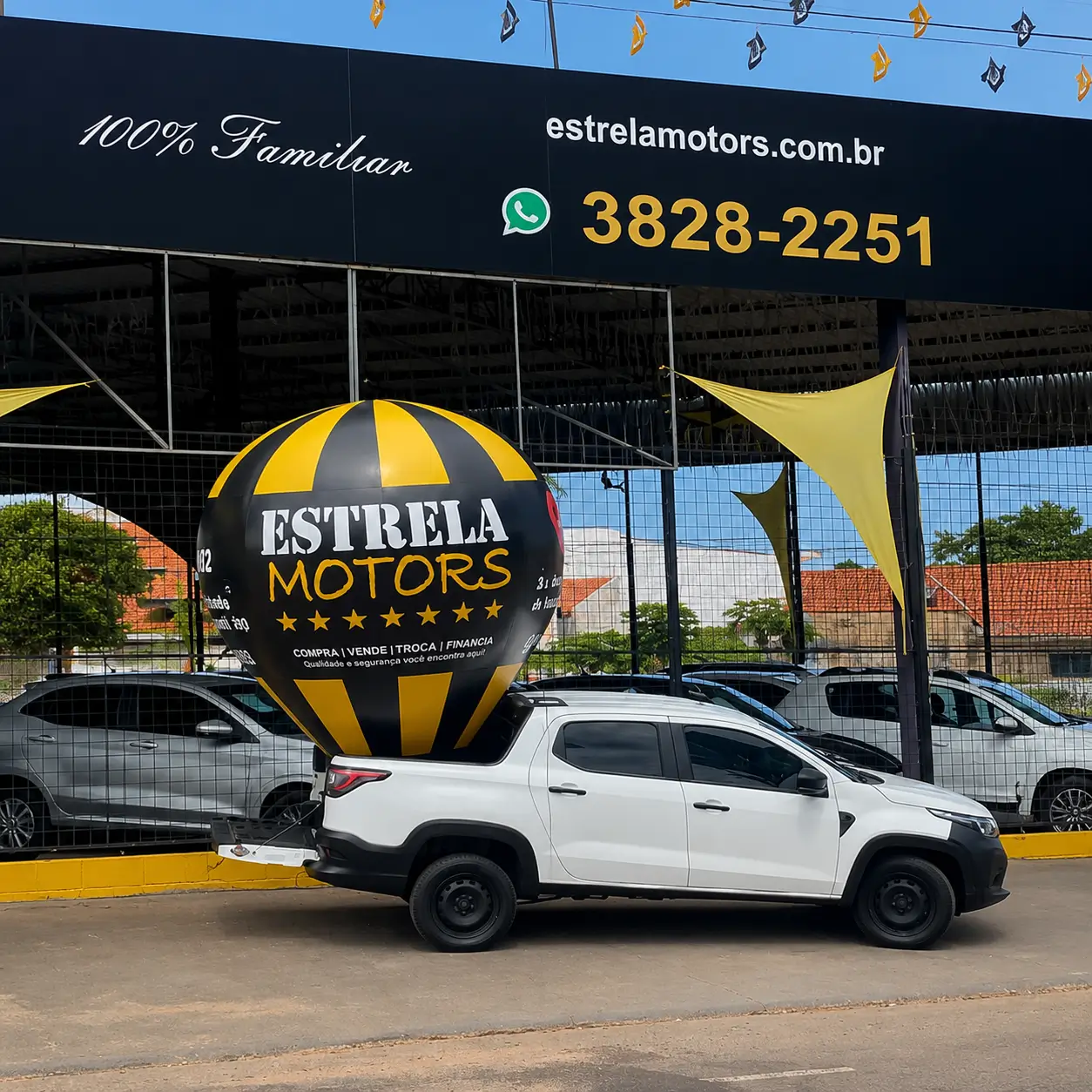 Balão inflável personalizado da Estrela Motors instalado em veículo promocional em frente à loja automotiva durante ação de divulgação.