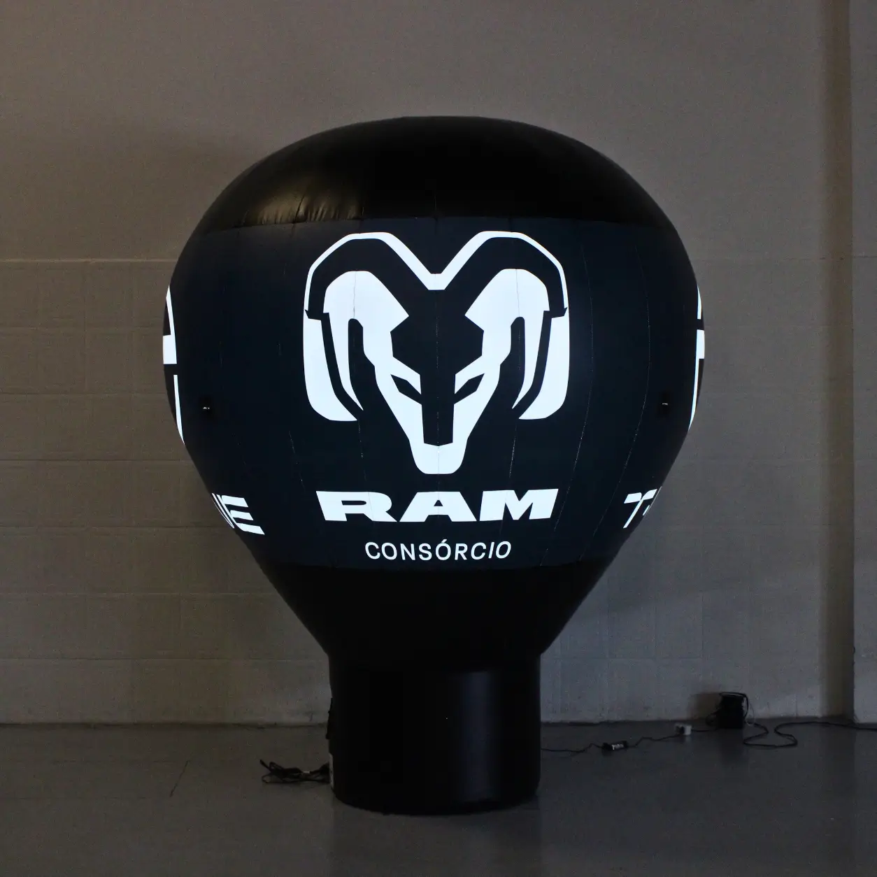Balão Inflável Promocional Iluminado RAM Consórcio 3 Metros — Financeira Automotiva Noturna | RVB Balões Balão inflável promocional RAM Consórcio de 3 metros iluminado pelo sistema LED interno padrão da RVB Balões em ação de marketing de financeira automotiva noturna, com logo e cores institucionais visíveis no escuro