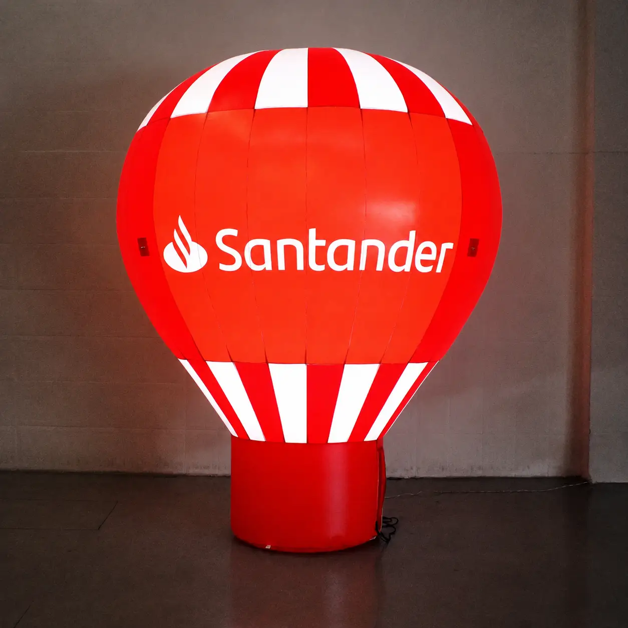 Balão Inflável Promocional Iluminado Santander 3 Metros — Marketing Financeiro Noturno | RVB Balões Balão inflável promocional Santander de 3 metros iluminado à noite com LED interno padrão da RVB Balões, mostrando cores Pantone do banco perfeitamente visíveis no escuro em ação de marketing financeiro