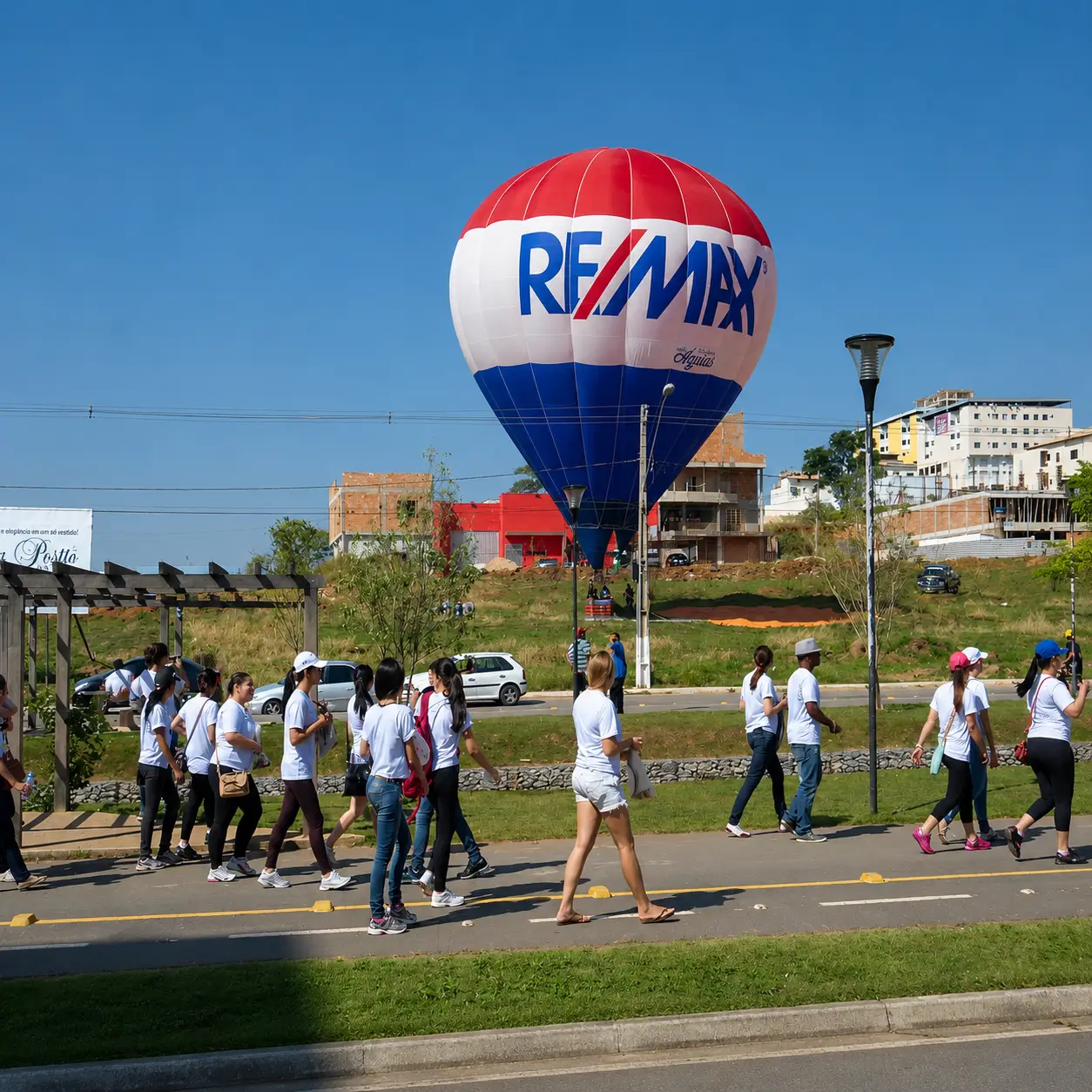 Balão de Ar Quente Personalizado RE/MAX — Ativação Urbana de Marca | RVB Balões Balão de ar quente totalmente personalizado RE/MAX com identidade visual completa em vermelho, branco e azul, ancorado em ativação urbana de marca operada pela RVB Balões