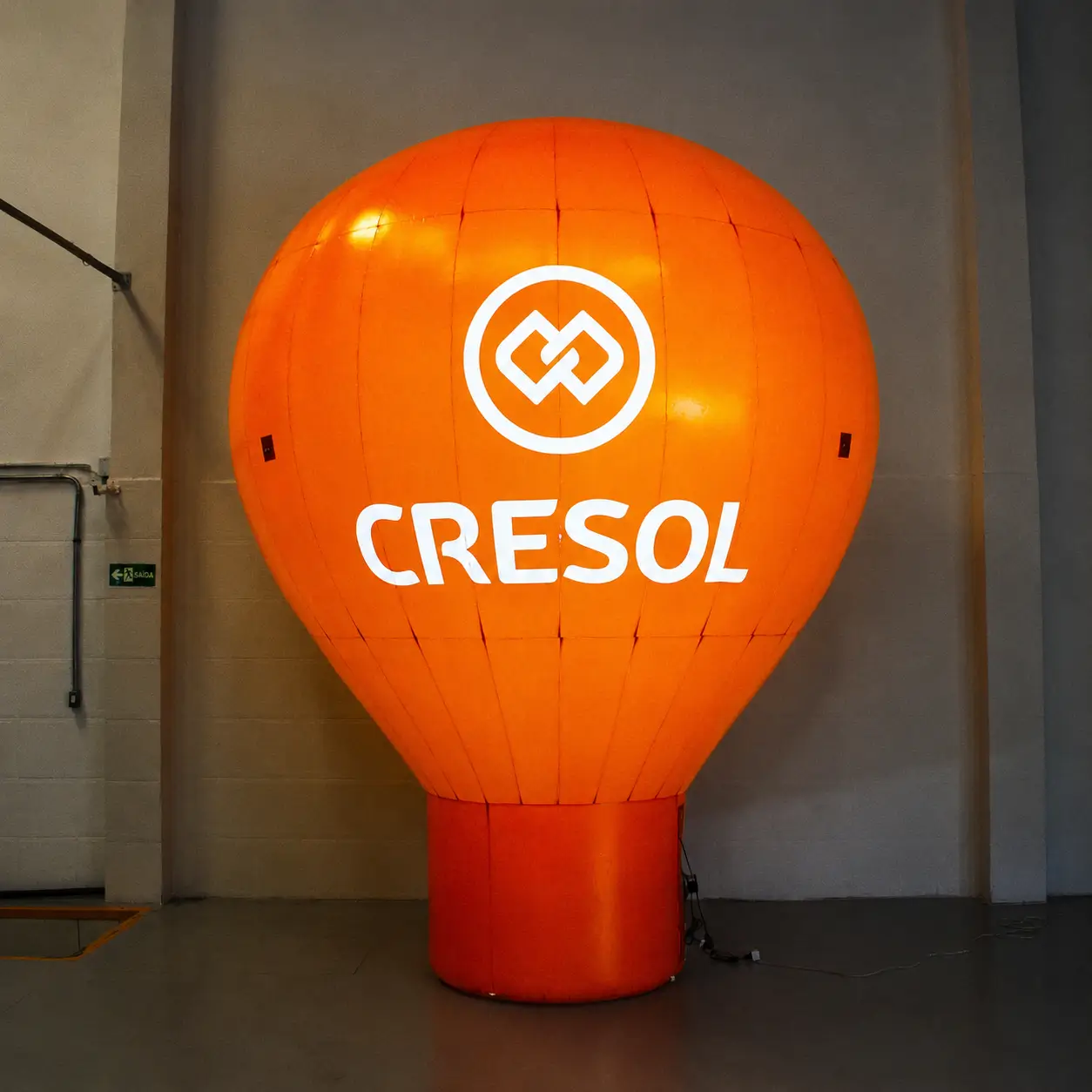 Balão Roof Top Iluminado Cresol 3 Metros — Cooperativa de Crédito em Evento Noturno | RVB Balões Balão Roof Top inflável Cresol de 3 metros iluminado à noite pelo sistema LED interno padrão da RVB Balões, brilhando de dentro durante evento de cooperativa de crédito com cores institucionais visíveis no escuro