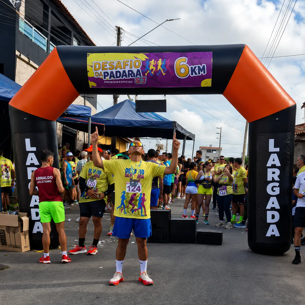 Portal inflável personalizado utilizado na largada de corrida de rua 6KM durante evento esportivo com atletas reunidos na linha de partida.