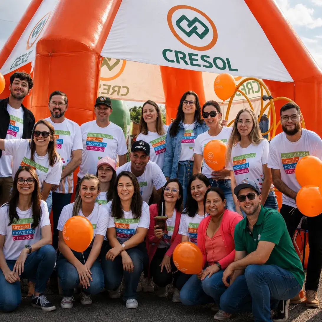 Equipe Cresol reunida na frente de tenda inflável personalizada laranja em evento da Agrishow, fabricada pela RVB Balões